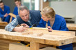 © auremar - carpenter teaching apprentice how to cut wood
