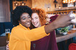 © Sanja - Two female friends taking a selfie in a bar.
