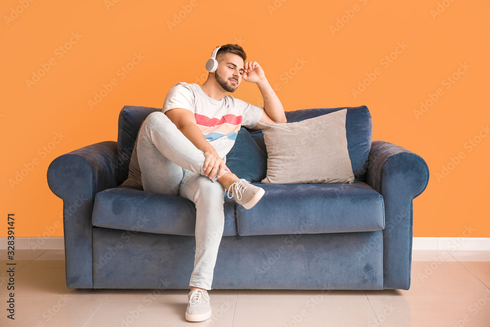 Young man listening to music while sitting on sofa at home