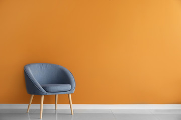 Comfortable armchair near color wall