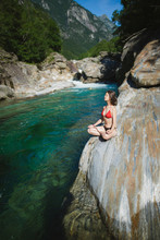 Woman Wearing Bikini Sitting On Rock By River