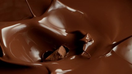 Wall Mural - Super slow motion of flying raw chocolate pieces splashing into molten chocolate. Filmed on high speed cinema camera, 1000fps.