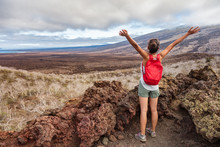 Galapagos Tourist Hiking On Santiago Island, Galapagos Islands, Ecuador, South America. Woman On Hike Visiting Landmark And Tourist Destination. Happy And Excited With Arms Raised Up In Sky.