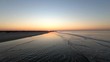 Aerial, rising drone shot over a beach and small waves on the Noordsee, at sunset, in Langeoog, North Germany