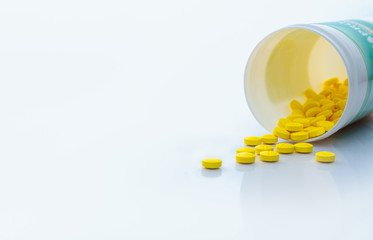 Canvas Print - Yellow tablets pills spread out of drug bottle. Tablets pills with bottle on white table. Drug production in pharmaceutical industry concept. Healthcare and medicine background. Medication use.