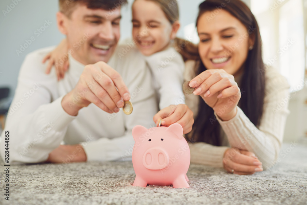 Happy family saves money in a piggy bank pig. Stock Photo | Adobe Stock