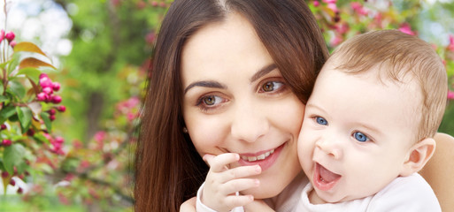 Canvas Print - family and motherhood concept - happy smiling young mother with little baby over natural spring cherry blossom background