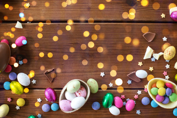 Wall Mural - easter, sweets and confectionery concept - chocolate eggs and candy drops on wooden background