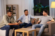 © Syda Productions - technology, leisure and people concept - man using smartphone and friends talking at home at night