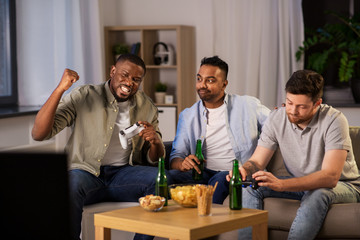 Wall Mural - friendship, technology and leisure concept - smiling male friends with gamepads and beer playing video game at home at night