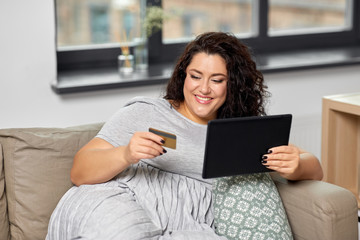 Wall Mural - technology, online shopping and people concept - happy smiling woman with tablet pc computer and credit card on sofa at home