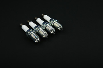 Wall Mural - set of 4 spark plugs on a black background with copy space