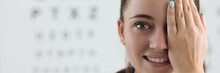 Portrait Of Lady Oculist Smiling And Looking At Camera With Happiness. Cheerful Doctor Standing In Clinic Office And Covering Left Eye With Tender Hand. Vision Test Concept