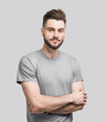 © kite_rin - Portrait of handsome smiling young man with folded arms. Smiling joyful cheerful men with crossed hands studio shot. Isolated on gray background