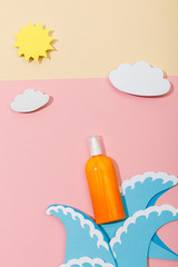 Wall Mural - Top view of paper cut sea waves, clouds, sun and bottle of sunscreen on pink and beige