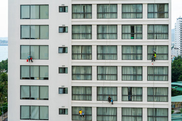 Asian industrial worker cleaning windows of a modern building.