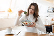 young beautiful woman looks unsatisfied with quality of salad holding piece of green leaf, looking unhappy during lunch time at cafe, , complaining guest concept
