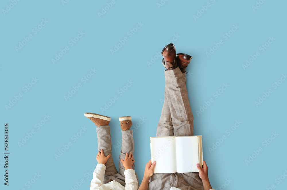 Father and young son sit and read a book - obrazy, fototapety, plakaty 