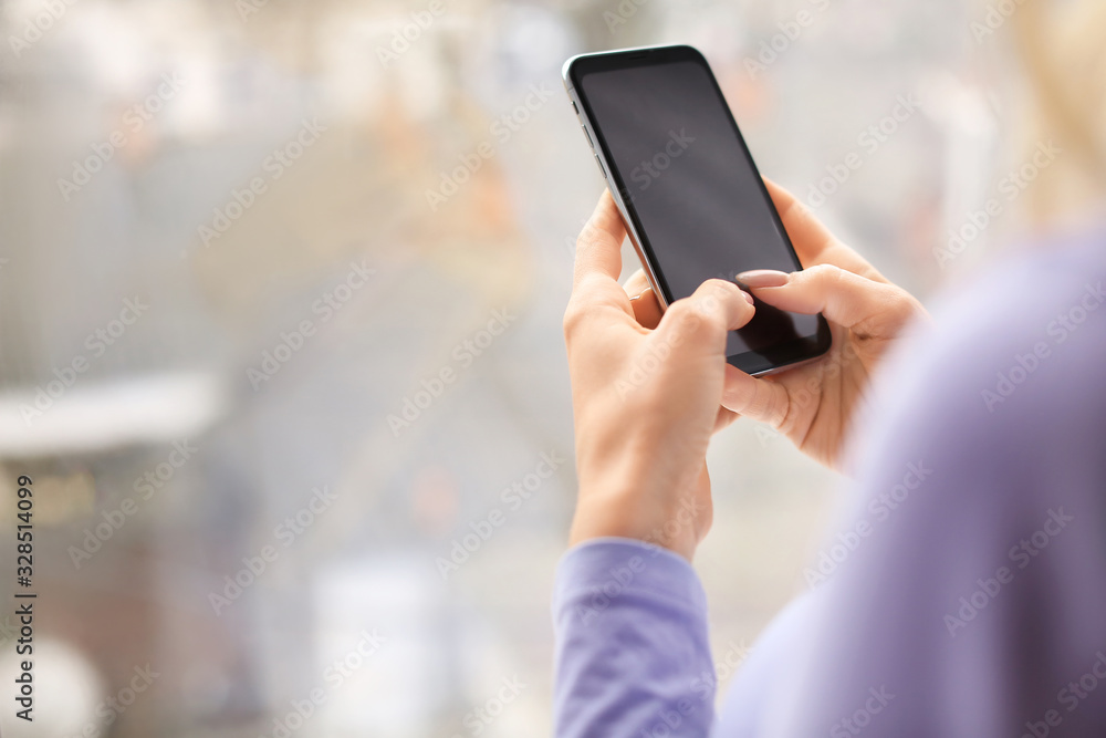 Young woman with mobile phone near window