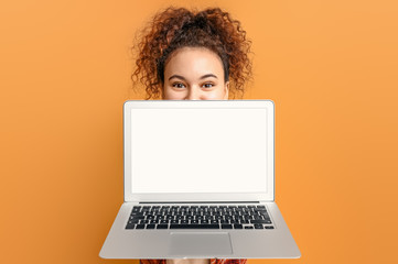 Beautiful young African-American woman with laptop on color background