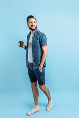 Wall Mural - Beautiful bearded young man drinking coffee or tea in a paper Cup