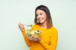 © luismolinero - Young woman with salad over isolated green wall