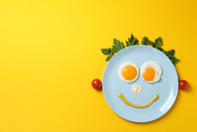 Smile Face Made Of Plate With Fried Eggs On Yellow Background, Top View