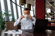 © Konstantin Zibert - Young businessman wearing a white fashion shirt enjoying a coffee in a cafe with a laptop, documents and a phone. Freelance and selfemployment concept. Distance dream job.