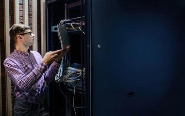 In the server room a technician/ It engineer/ hold the notebook