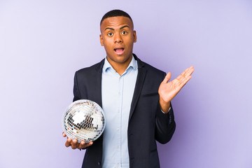 Wall Mural - Young latin man holding a ball party isolated surprised and shocked.