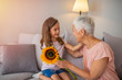 © Dragana Gordic - Cute girl giving a bunch of flowers to her grandmother. Happy senior grandma hugging granddaughter thanking for gift and flowers. Girl giving flowers bouquet congratulating smiling grandma