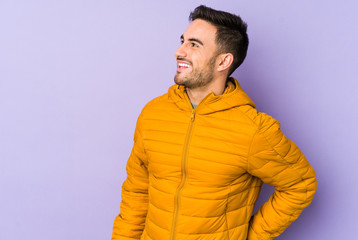 Young caucasian man isolated on purple background relaxed and happy laughing, neck stretched showing teeth.