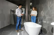 © Тарас Нагирняк - Young woman choosing new bathroom furniture standing near the showcase with white acrylic bathtubs in the plumbing shop