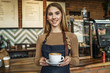 © Тарас Нагирняк - Cute woman waitress holding cup with coffe latte while stay near bar counter