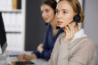 © rogerphoto - Businesswoman talking by headset while sitting in office. Call center and diverse people group in business