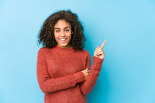 Young African American Curly Hair Woman Smiling Cheerfully Pointing With Forefinger Away.