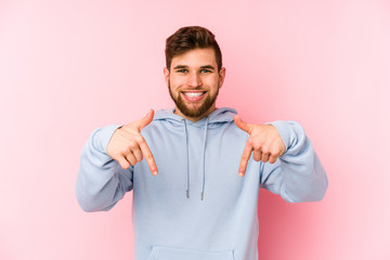 Canvas Print - Young caucasian man isolated on pink background points down with fingers, positive feeling.