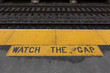 sign at the railroad station at the edge of the platform looking toward the tracks warning you to watch the gap