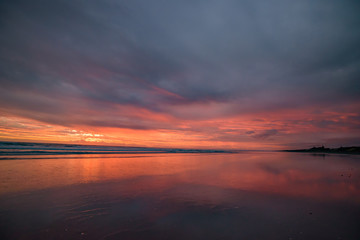 Muriwai Beach at sunset time with colorful clouds, New Zealand