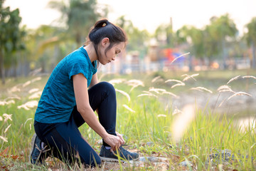 Wall Mural - Asian girls are preparing by wearing shoes to exercise in the park.