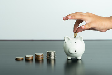 Money saving and donation concept, child put money on cute white piggy bank