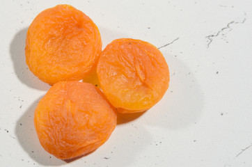 A few berries of bright dried apricots on a background of textural black and white surface.