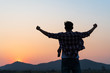 Man with fist in the air during sunset sunrise mountain in background. Stand strong. Feeling motivated, freedom, strength and courage concept.