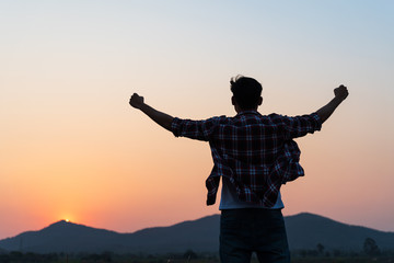 man with fist in the air during sunset sunrise mountain in background. stand strong. feeling motivat