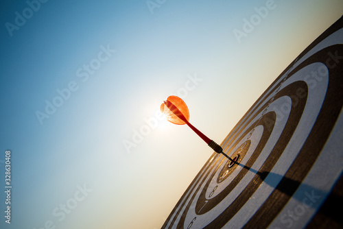 Fotomural Close up shot red darts arrows in the target center on dark blue sky background