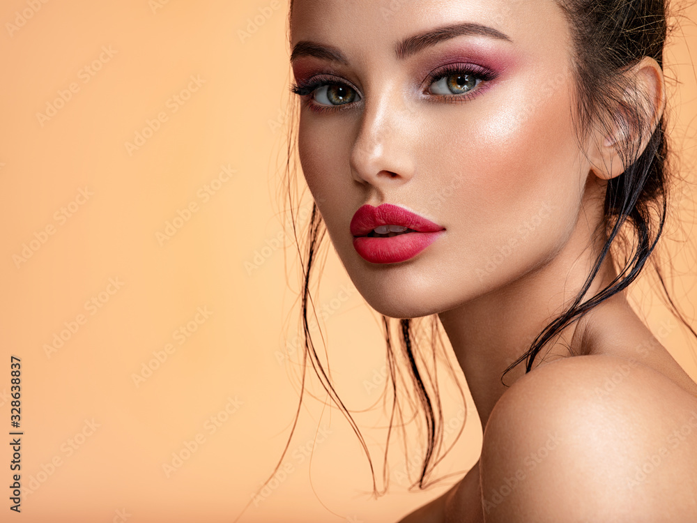 Beautiful white girl with red lips looks to the camera. Stunning brunette girl. Closeup face of young beautiful woman with a healthy clean skin. Pretty woman with bright  makeup of eyes. - obrazy, fototapety, plakaty 