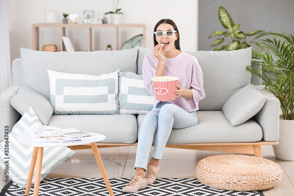 Young woman watching movie while sitting on sofa at home