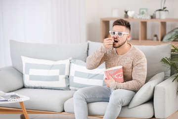 Canvas Print - Young man watching movie while sitting on sofa at home