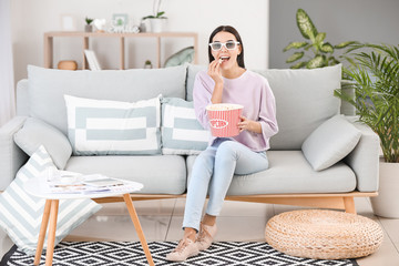 Sticker - Young woman watching movie while sitting on sofa at home