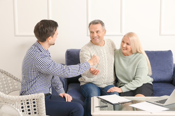 Poster - Real estate agent giving a key from new house to mature couple